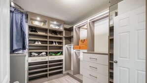 A walk-in closet with multiple shelves for shoes, a hanging rack, and a mirrored section. - Luxury Lagoon Smart Home in Epperson (Wesley Chapel)
