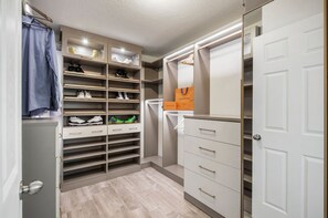 A walk-in closet with multiple shelves for shoes, a hanging rack, and a mirrored section. - Luxury Lagoon Smart Home in Epperson (Wesley Chapel)