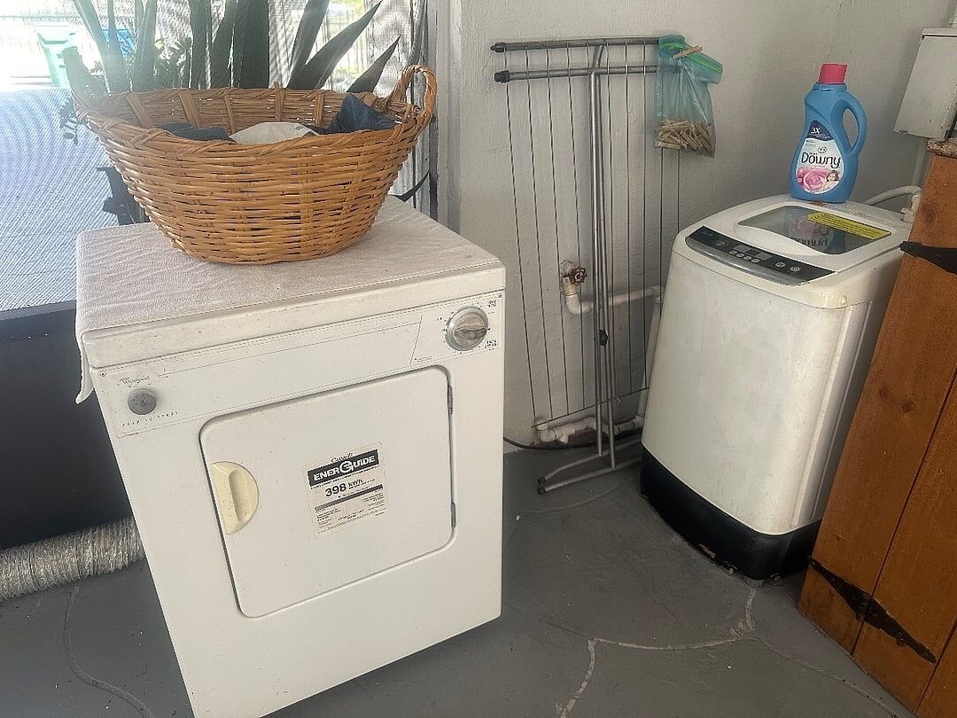 A compact laundry area with a washing machine, a dryer, and a wicker basket on top of the washing machine.