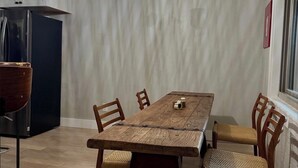 Un comedor con una mesa y sillas de madera, una lámpara colgante y un armario oscuro.