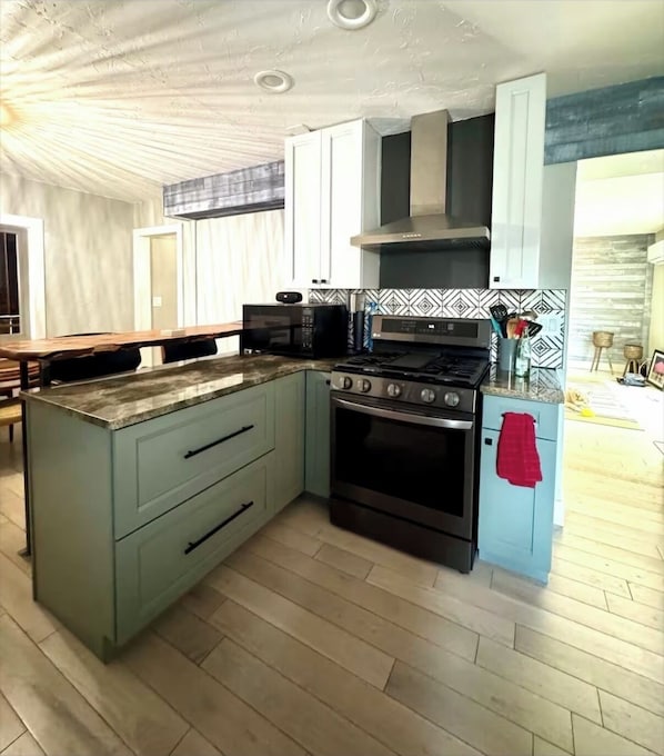 A kitchen with a central island, a stove, and a microwave.