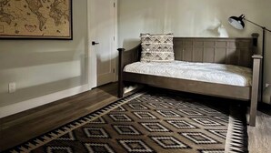 Un dormitorio con cama, un tapete estampado, un mapa del mundo en la pared y una lámpara.