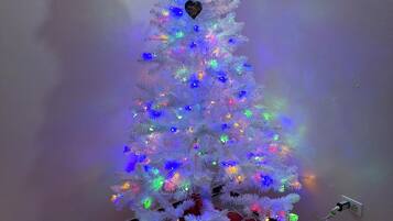 Un árbol de Navidad con luces multicolores y una figura de muñeco de nieve en la parte superior.
