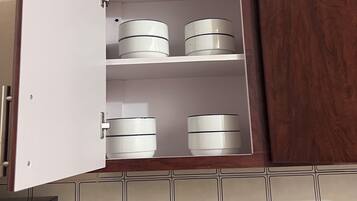 A kitchen with a white cabinet containing three white containers.