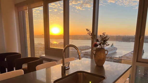 A modern kitchen with a large window, a stainless steel sink, and a vase with flowers. - Luxe 2 bedroom apartment in Midtown - 24 hour doorman (New York)