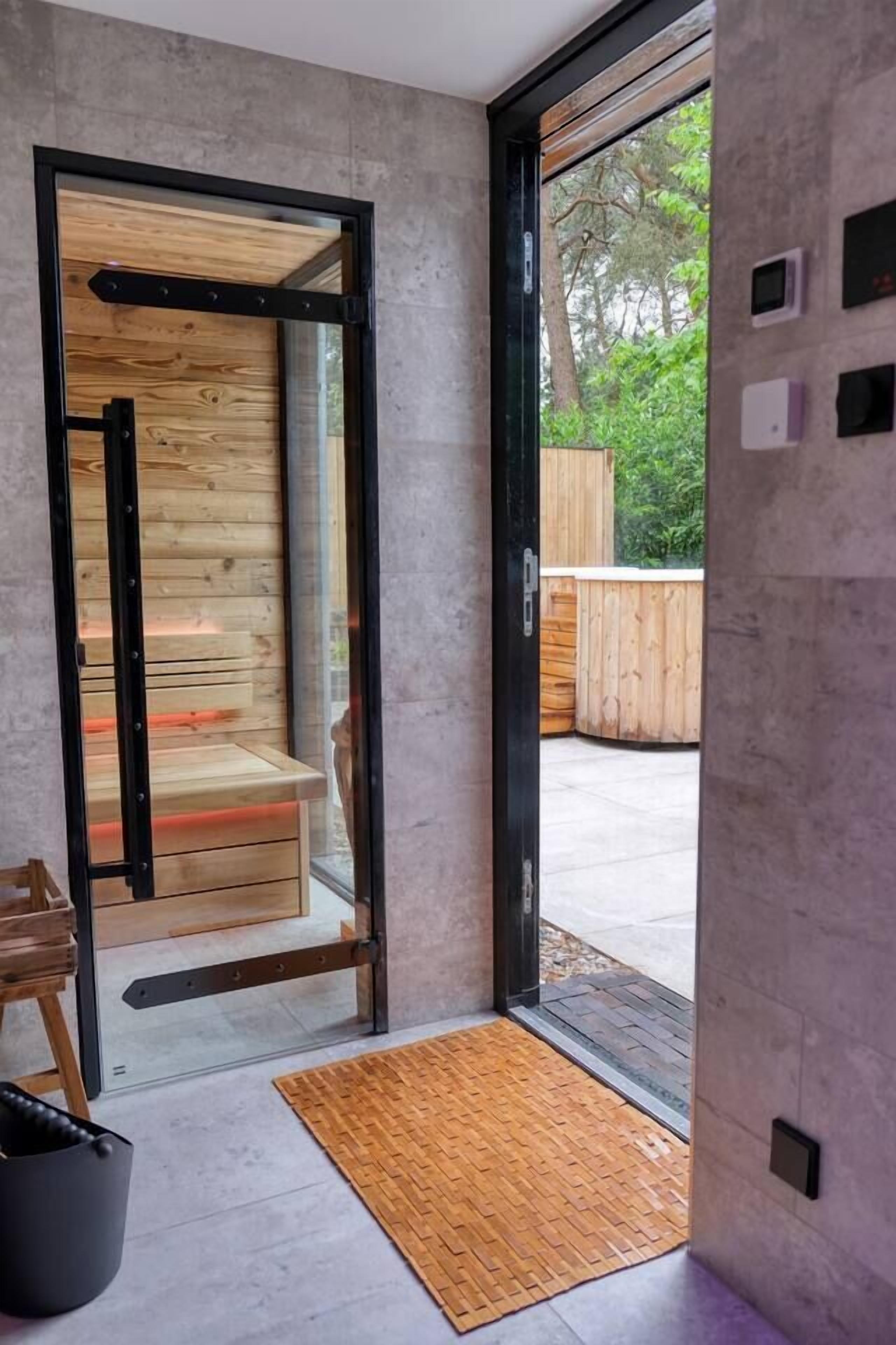 A modern interior with a wooden bench and a black metal frame door leading to an outdoor area.