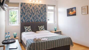 A bedroom with a bed, two nightstands, a ceiling fan, and a window with a view of greenery.