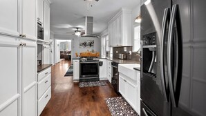 Una cocina moderna con armarios blancos, electrodomésticos de acero inoxidable y piso de madera.