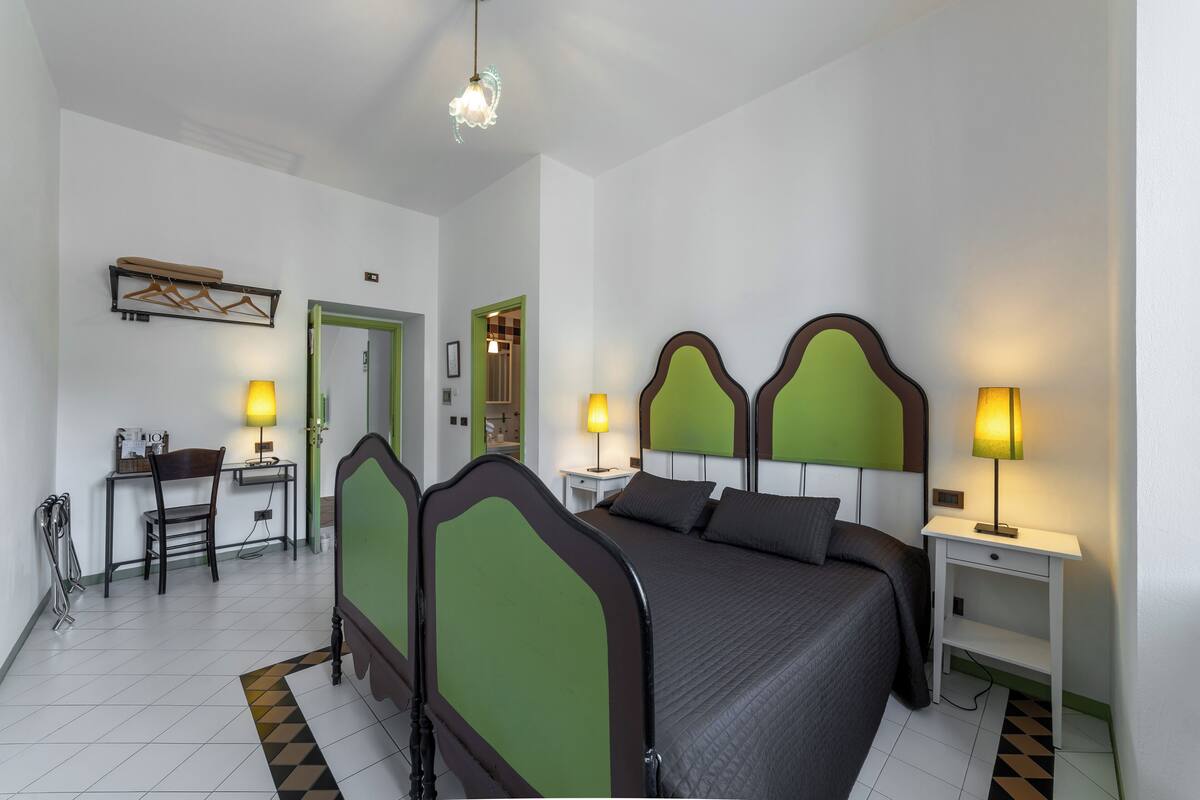 A hotel room with a bed, two bedside tables, a desk, and a chair.