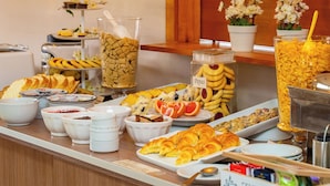 Un bufé con diversas opciones de comida, como frutas, pasteles y cereales.