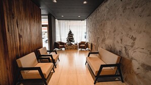 Un área de recepción con paneles de madera, un árbol de Navidad y cuatro sofás dispuestos en semicírculo.