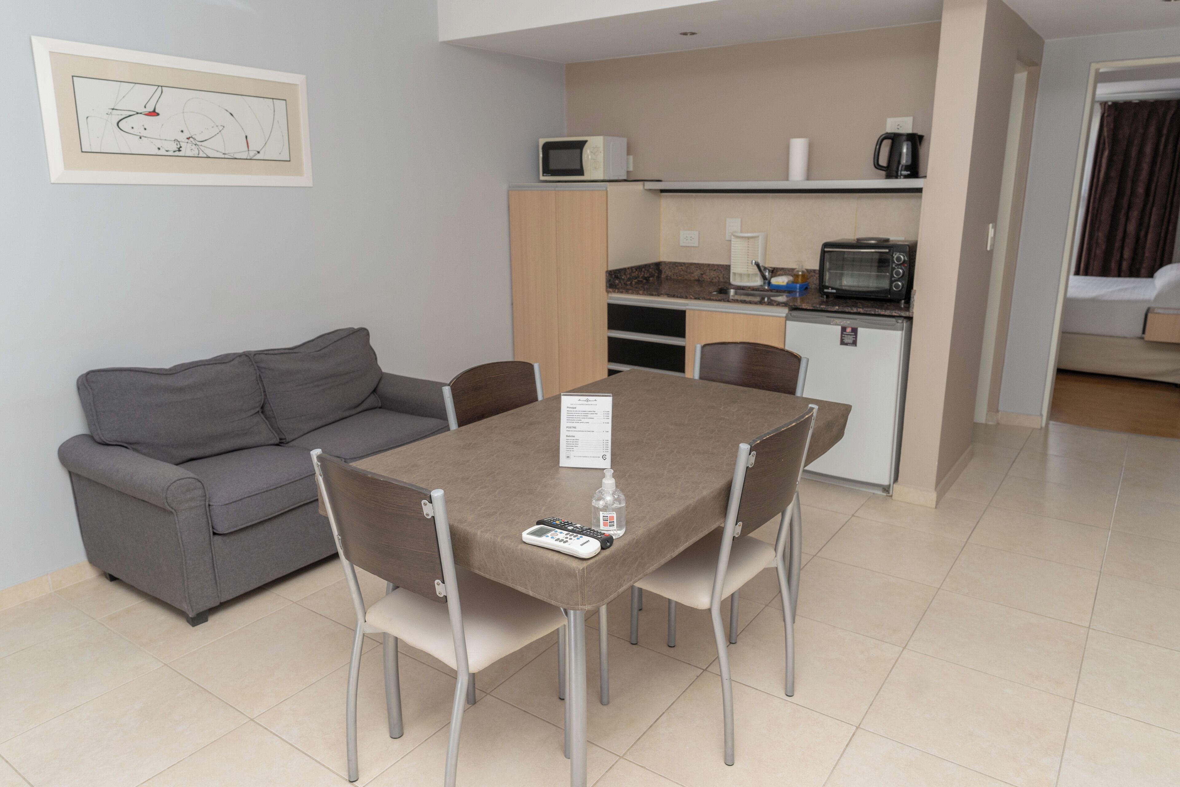 Un espace de vie compact comprenant un coin cuisine, un coin repas avec une table et des chaises, un canapé et un lit dans la pièce adjacente.