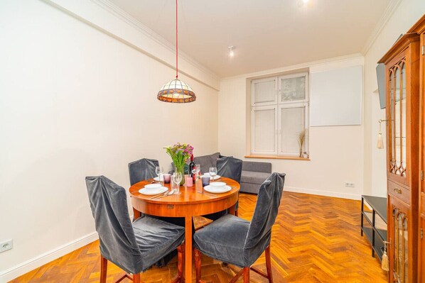 A dining area with a round wooden table set for four, surrounded by grey upholstered chairs.