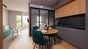 Una cocina moderna con una mesa de comedor de madera, sillas verdes y una encimera negra.