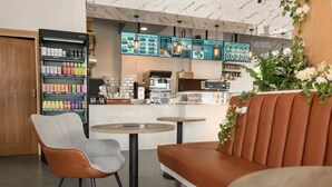 Ein modernes Café mit Sitzgelegenheiten, einer Kaffeemaschine und einer Speisekarte.