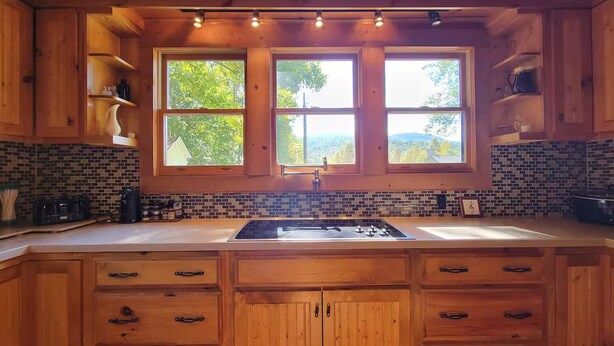 A wooden kitchen with a large window, a sink, and cabinets. - Charming 3-bedroom cabin in beautiful Boomer with AC (Boomer)