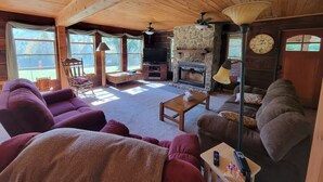 A cozy cabin interior with wooden beams, a stone fireplace, and a comfortable seating area. - Charming 3-bedroom cabin in beautiful Boomer with AC (Boomer)