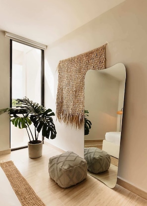 A modern room with a large mirror, a potted plant, and a woven wall hanging.