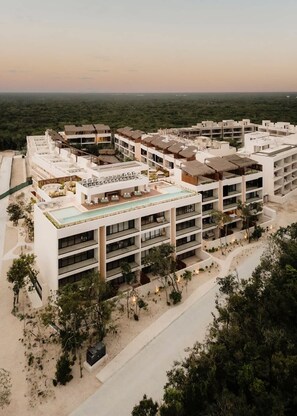 A resort with multiple buildings, a rooftop pool, and a beach area.