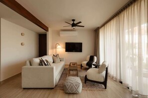 Un salon moderne avec un canapé, des fauteuils, une table basse et un ventilateur de plafond.