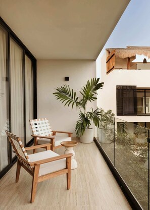 Un balcon avec des chaises en bois, une petite table et des plantes en pot.