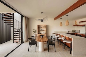 A modern kitchen with a central island, wooden chairs, and pendant lights.