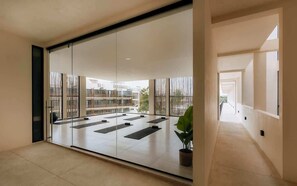 A modern interior with a glass partition, a yoga mat area, and a potted plant.
