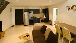 A modern apartment with a living room, kitchen, and dining area. There is a staircase leading to an upper floor. - premier luxury apartment (Accra)
