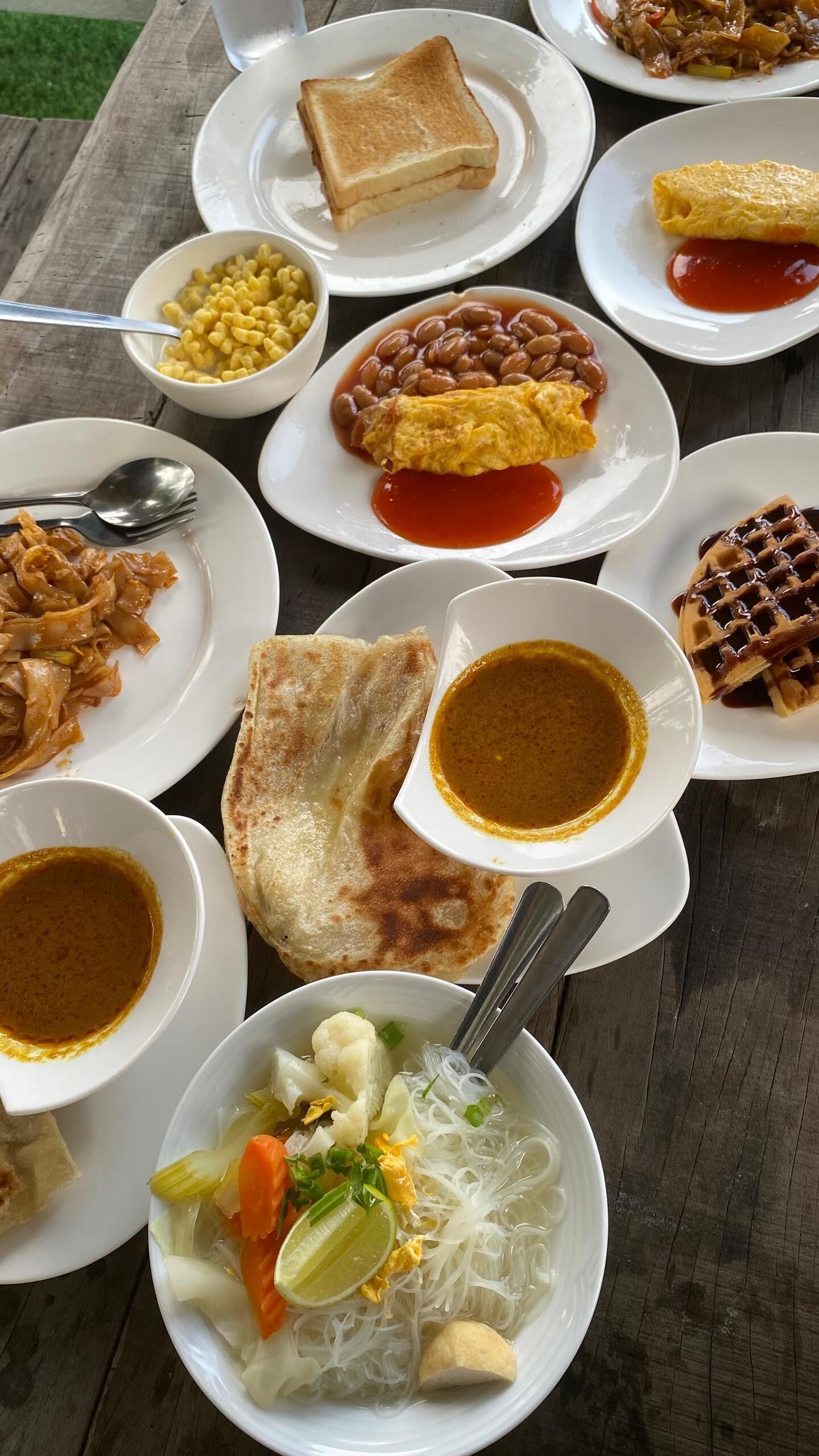 A variety of dishes including noodles, a waffle, and a plate of beans.