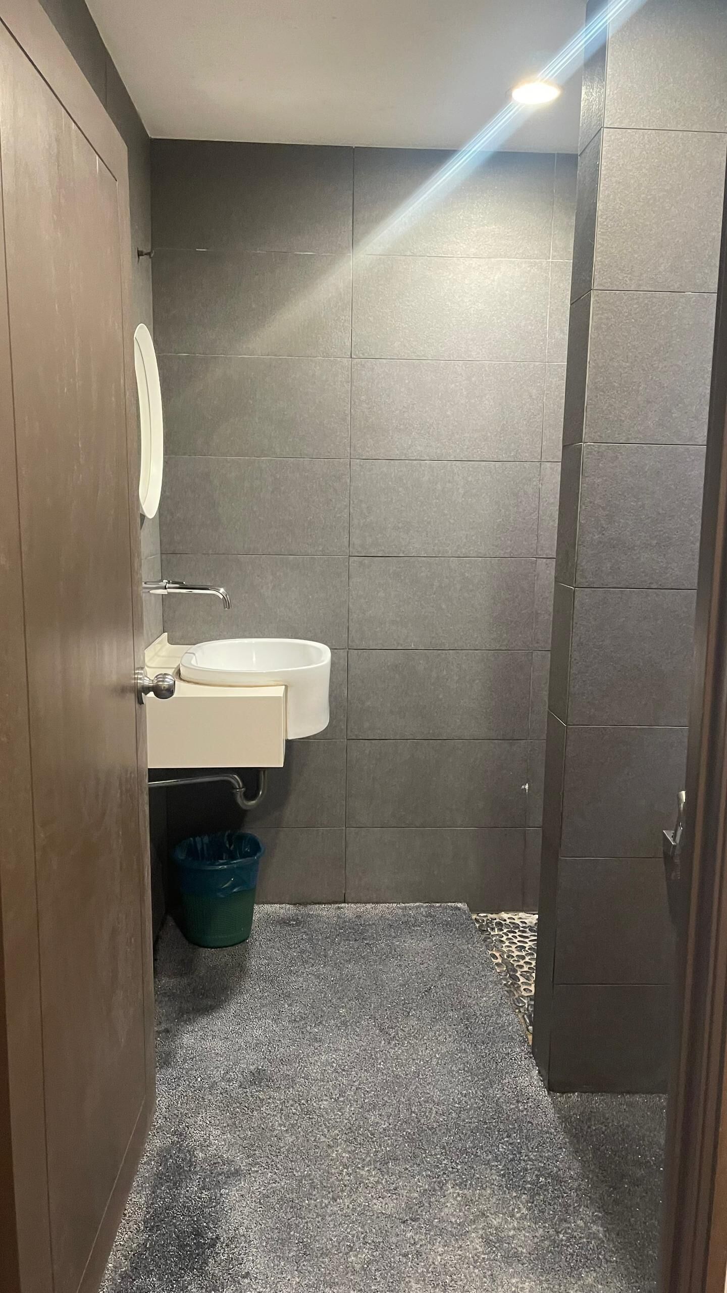 Un baño pequeño con puerta de madera, lavabo blanco y espejo.