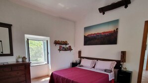 A bedroom with a bed, a dresser, a window, a painting, and a shelf with decorative items. - Evening Rose - Dream vacation in Tuscany with private spa, near 5 Terre (Toscana)