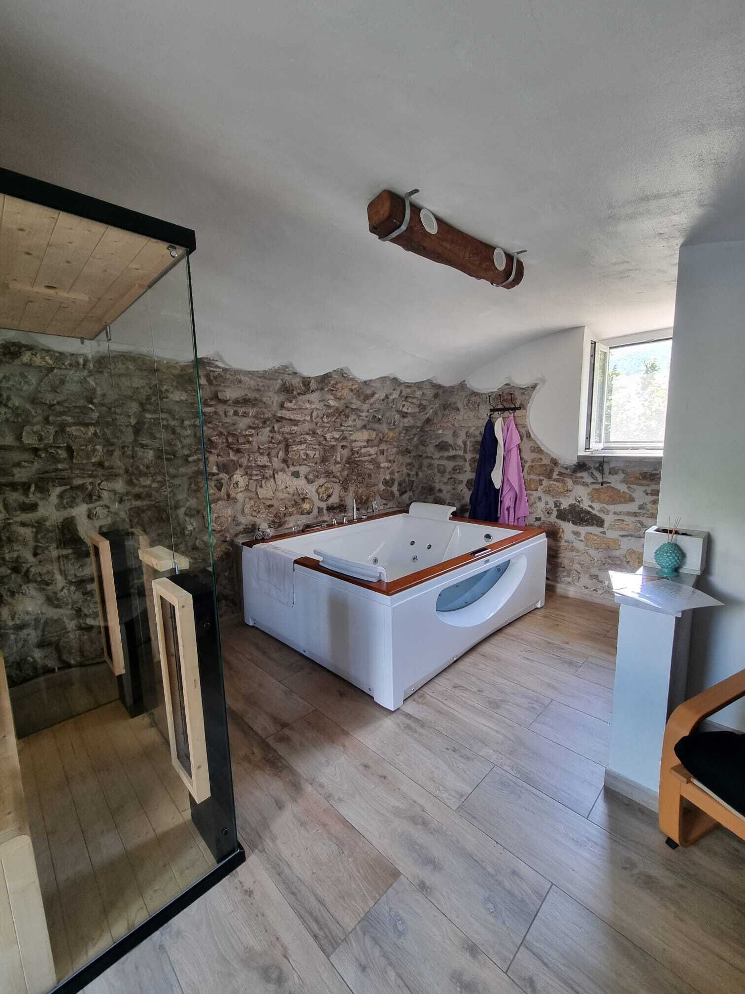 Una stanza con parete in pietra, soffitto in legno, un letto grande e una finestra.