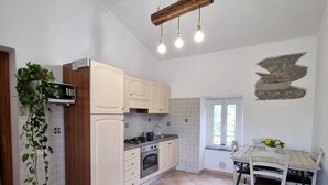 A spacious kitchen with white cabinets, a wooden ceiling beam, and a dining area with a white table and chairs. - Evening Rose - Dream vacation in Tuscany with private spa, near 5 Terre (Toscana)