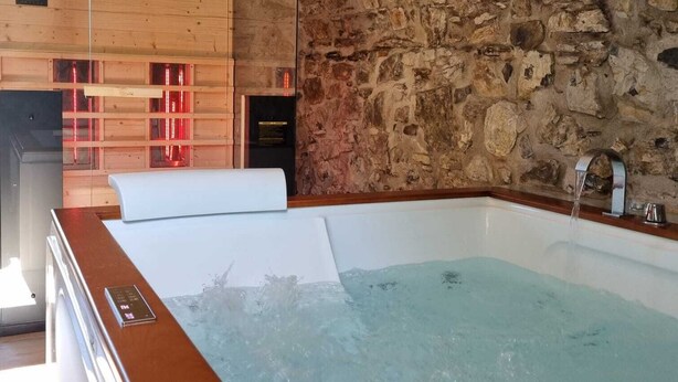 A modern bathroom with a stone wall, a wooden bathtub, and a digital control panel. - Evening Rose - Dream vacation in Tuscany with private spa, near 5 Terre (Toscana)