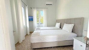 Una camera d'albergo con due letti, una TV e un condizionatore d'aria.