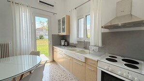 Eine moderne Küche mit Glastisch, Holzschränken, einem Herd und Blick auf eine Wohngegend.