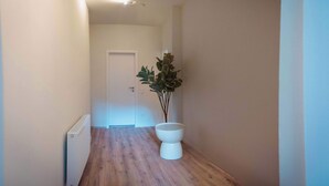 A narrow hallway with wooden flooring, a white radiator, and a potted plant. - Boutique Suite by the Park w Parking (Celle)