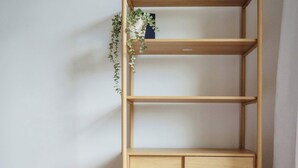 Ein Holzbücherregal mit drei Einlegeböcken und einem Unterschrank, vor einer schlichten Wand und einem Holzboden.
