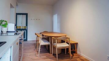 A modern kitchen with a wooden dining table and chairs, a built-in oven, and a potted plant.