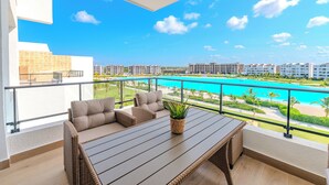 Un balcone con mobili in vimini e vista su una piscina e una spiaggia.