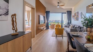 Un salon moderne avec un coin repas, de grandes fenêtres et une vue sur les immeubles.