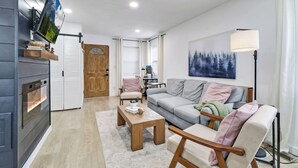 Un salon moderne avec une cheminée, un canapé, une table basse et un téléviseur fixé au mur.