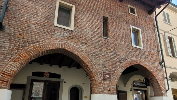 Ein historisches Gebäude mit Ziegelbogen und einem Schild mit der Aufschrift 'Casa'.