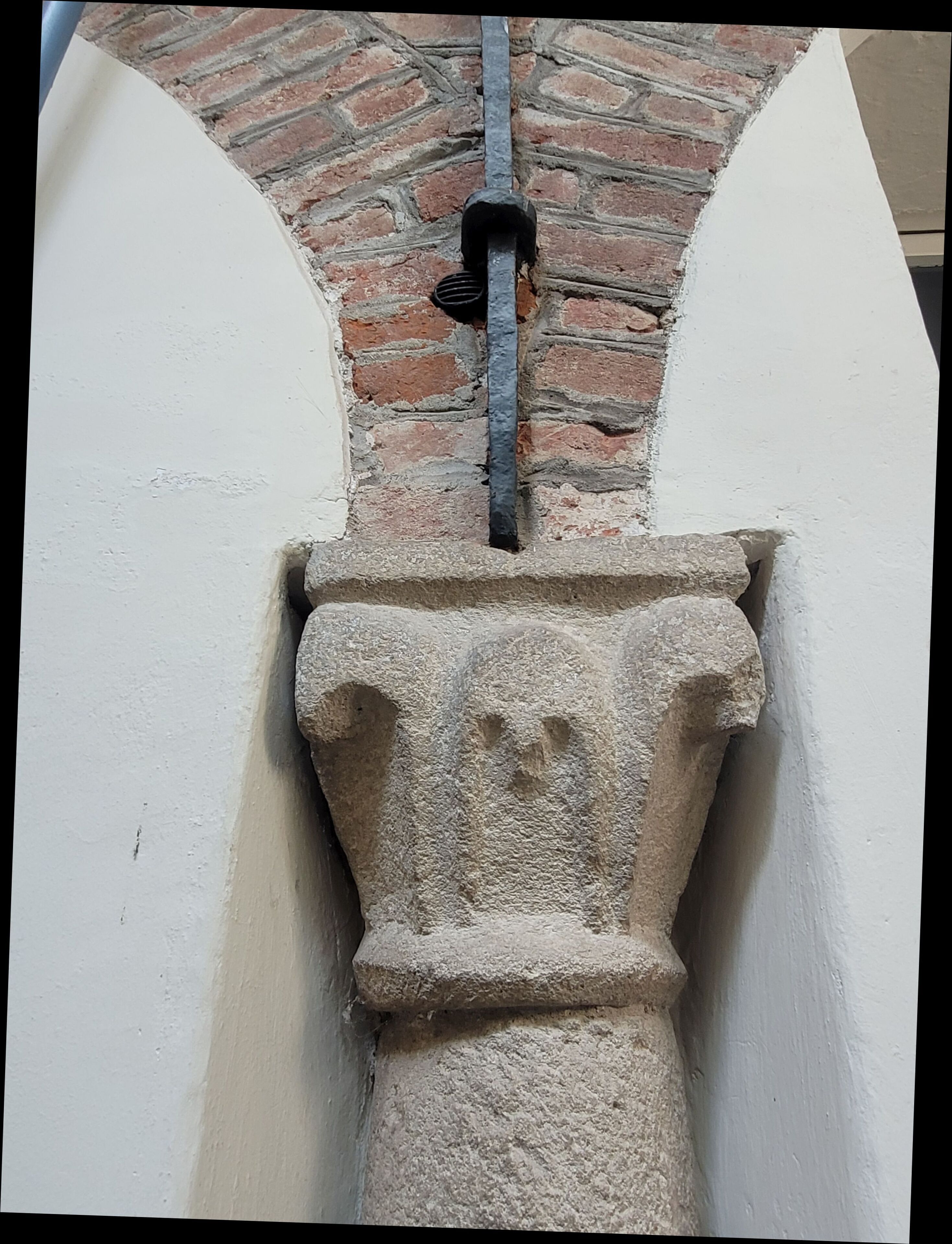 Un élément architectural en pierre, surmonté d’une tige métallique.