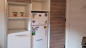 Eine kleine Küche mit integriertem Kühlschrank und Holzschränken.