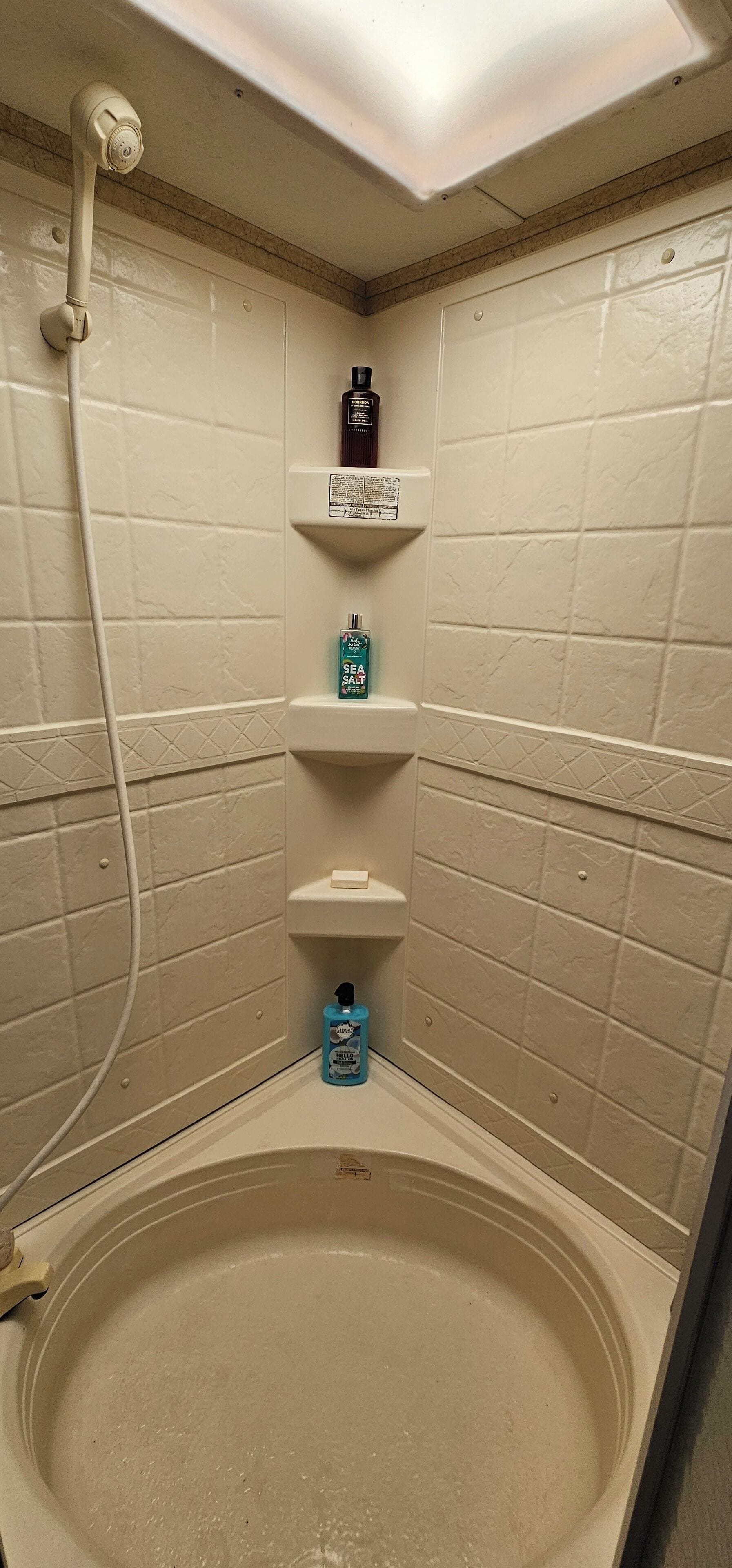 Une salle de bain avec une baignoire, un sèche-mains et des articles de toilette rangés sur une étagère.