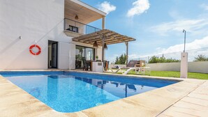 A swimming pool with a covered patio area, a lifebuoy, and a barbecue grill. - Elegant and modern detached villa with swimming pool (Santanyí)