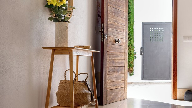 A modern interior with a wooden door, a mirror, a woven basket, and a potted plant. - Elegant and modern detached villa with swimming pool (Santanyí)