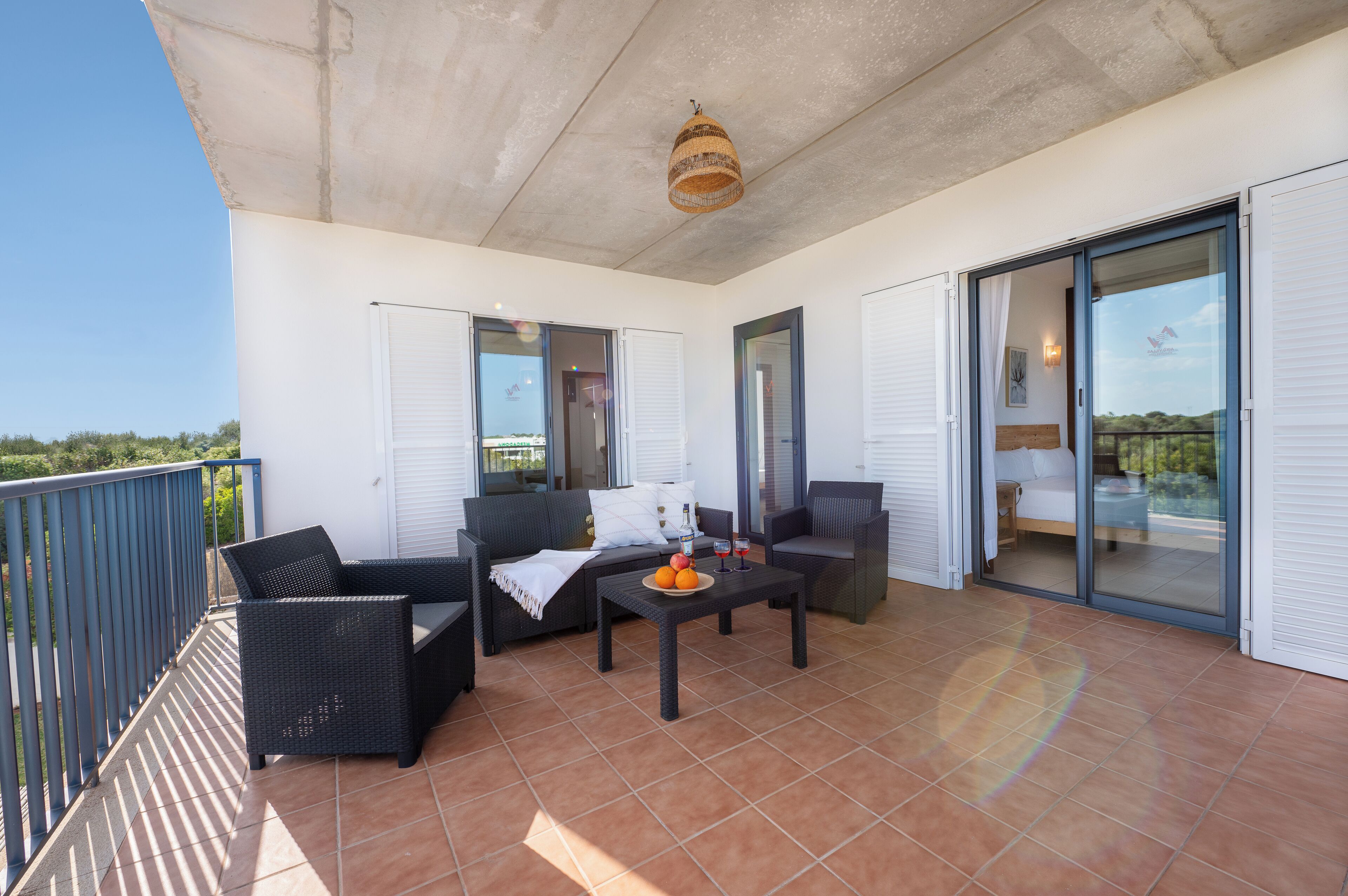 Een balkon met buitenmeubilair, een tafel met fruit en uitzicht op het landschap.