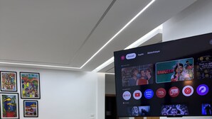 A modern living room with a large flat-screen TV displaying various apps and a bookshelf.